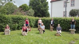 Schülerinnen mit ihren Nistkästen auf der Wiese