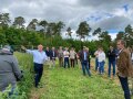 Mehrere Personen auf einem Feld. Der Betriebsleiter erklärt den Anbau.