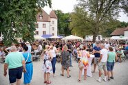 Viele Menschen stehen und sitzen unter freiem Himmel zusammen.