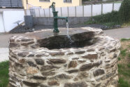 Aus einem Wasserhahn läuft Wasser in einen Brunnen.