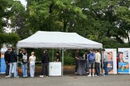 Unter einem Pavillon wird zwei Gruppen von jeweils sechs Schülern eine Erklärung zum Thema Geodäsie gegeben. 