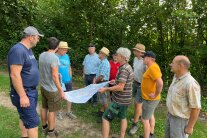 Eine Gruppe Personen bespricht einen Plan im Wald.