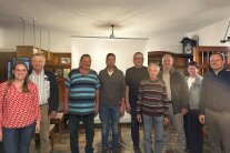 Neun Personen haben sich zum Gruppenfoto aufgestellt. 