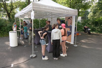 Unter einem Pavillon stehen Schüler und Mitarbeiter des Amtes für Ländliche Entwicklung an Stehtischen und unterhalten sich. 
