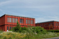 Das rote Amtsgebäude des ALE Oberpfalz mit Büschen und Blumen davor.