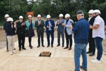 Viele Personen stehen um ein Loch am Boden, in das eine Kassette versenkt wurde. 
