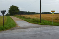 Asphaltierte Zufahrt in schlechtem Zustand, die durch Felder zum Weiler Sommerlegerl führt.