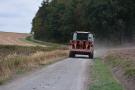 Mähdrescher fährt auf einem Wirtschaftsweg. Das Fahrzeug fährt teilweise auf dem Bankett.