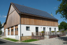 Dorfgemeinschaftshaus mit massivem, weiß gestrichenen EG und bretterverschaltem Dachgeschoss