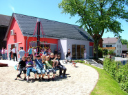 Kinder auf dem Spielplatz; im Hintergrund neu geschaffenes Gemeinschaftshaus