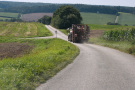 Traktor mit Anbaugerät fährt in der Flur auf 4 Meter breiter Gemeindeverbindungsstraße.