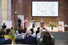 Vier Frauen auf einer Bühne stellen sich vor. Im Hintergrund eine Präsentation, im Vordergrund das Publikum.