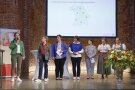 Sieben Frauen stehen auf einer Bühne und stllen sich vor. In den Hintergrundist eine Präsentation projiziert.